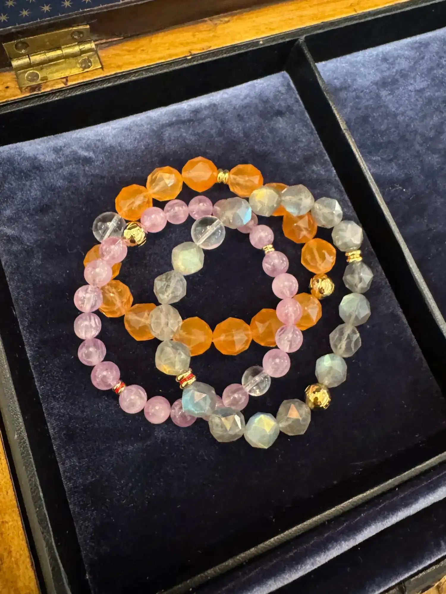 A colorful beaded bracelet set featuring faceted orange, pink, and clear gemstones with gold-toned spacer beads.