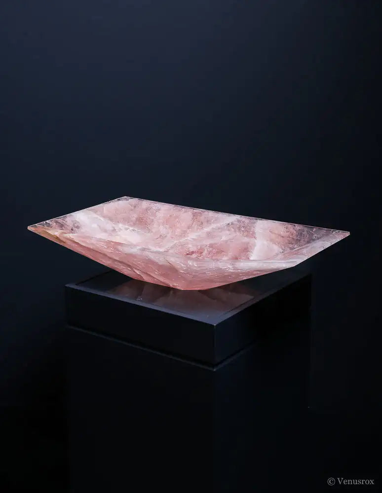 A rectangular, translucent pink rose quartz basin with natural veining and a smooth, polished surface.