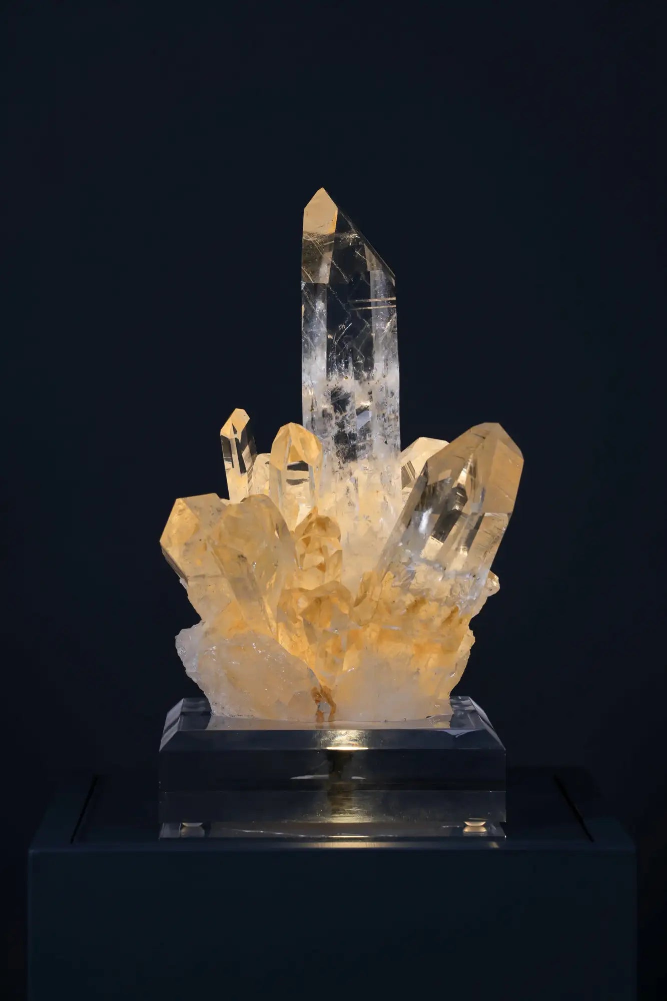 A translucent, golden-hued crystal cluster with a tall central spike and smaller facets radiating outward.
