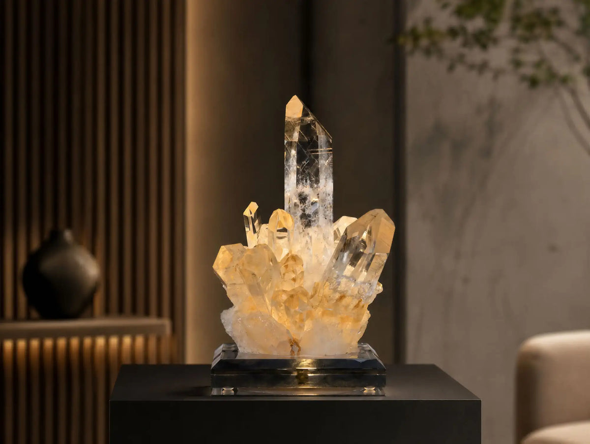 A glowing amber and clear quartz crystal cluster lamp with a sleek black base.