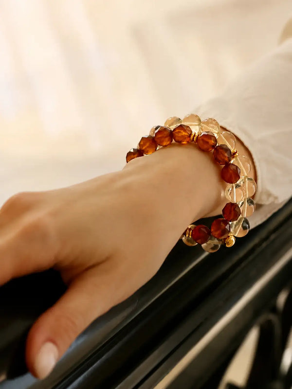 A delicate bracelet featuring alternating faceted amber and clear crystal beads, elegantly worn on a wrist.