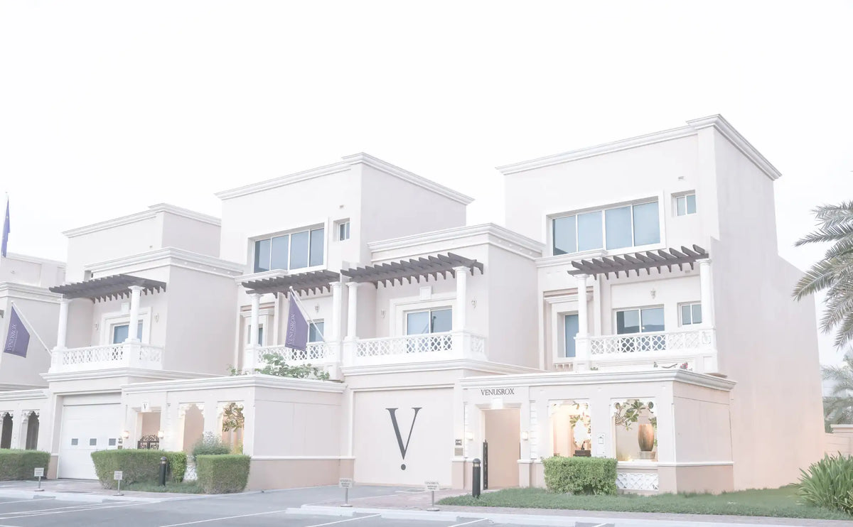 The building is a modern, two-story residential complex with light beige stucco walls and white decorative trim around windows and balconies.