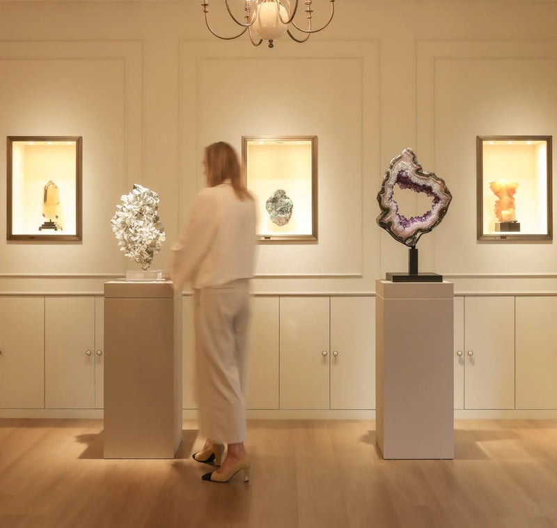 A striking purple and white geode specimen displayed on a pedestal in an elegant gallery setting.